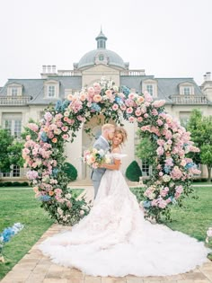 a bride and groom standing in front of a wedding arch with pink flowers on it