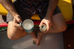 a man sitting on the ground holding a can of beer