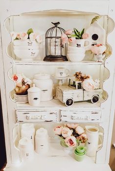 a white cabinet with flowers and dishes on it