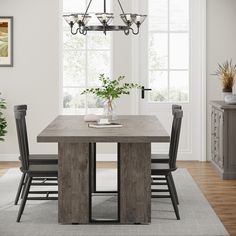 a dining room table and chairs in front of a window with potted plants on it