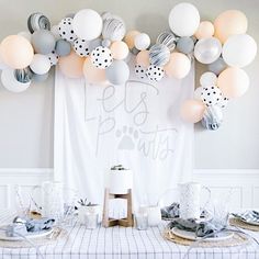 the table is set for a party with white and gray balloons, silverware, and polka dot napkins