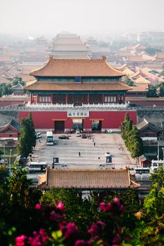 an aerial view of the forbidden city with flowers and buildings in the foreground on a foggy day