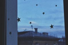 stars are flying in the sky from a window sill at dusk, with a building in the background