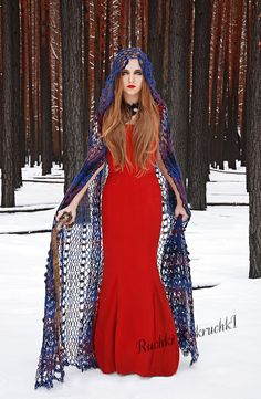 a woman in a red dress and blue shawl stands in the snow with her hands on her hips