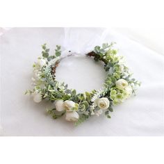 a wreath with white flowers and greenery is on a tableclothed surface in the shape of a circle