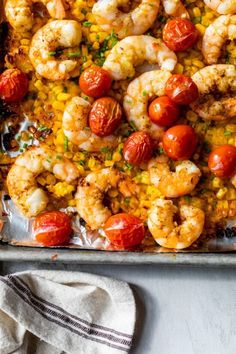 a sheet pan filled with shrimp, tomatoes and corn