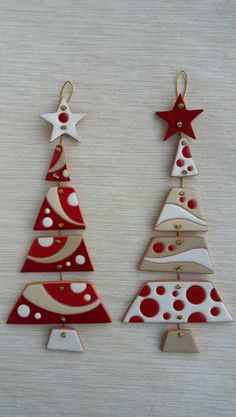 three christmas tree ornaments hanging from strings on a wooden table with white and red decorations