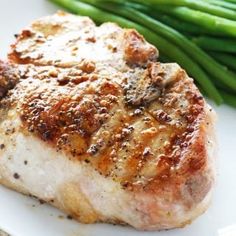 some meat and green beans on a white plate