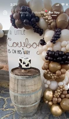 a cake sitting on top of a wooden barrel next to balloons