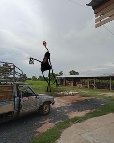 an odd looking statue in the middle of a road next to a truck and building