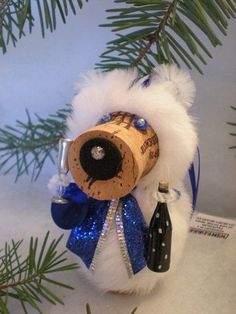 a wine cork ornament hanging from a christmas tree with blue and white ribbon