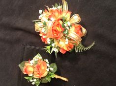 two bouquets of flowers are sitting on a black tablecloth with white and orange accents