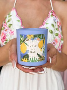 a woman holding a candle in her hands with the words amalfi be mar printed on it