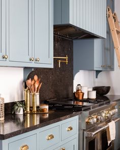 a kitchen with blue cabinets and gold accessories on the counter top, along with an oven