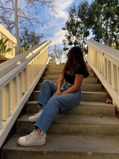 a woman sitting on the stairs with her legs crossed