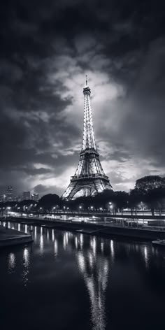 the eiffel tower is lit up in black and white with lights reflecting on the water