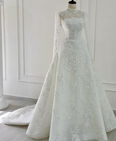 a wedding dress on display in front of a white wall with an open back and long sleeves