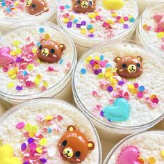 there are many desserts in plastic containers with teddy bears and confetti on them