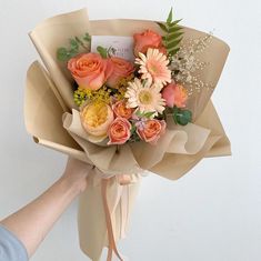 a person holding a bouquet of flowers in their left hand and the other hand with an envelope