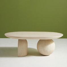 a white table with two wooden balls on it and a green wall in the background