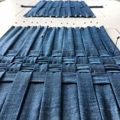 two rows of blue jeans laid out on top of a white table with pins in them