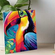 a colorful toucan bird art board print on a table next to a potted plant