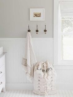 a white and gray bathroom with two towels hanging on the wall next to a window