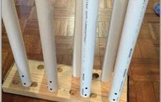 four white plastic pipes are lined up on a wooden stand