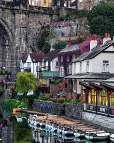 boats are docked in the water next to some buildings and a bridge with a stone arch