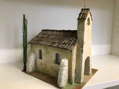 a small house with a cactus on top of it in a shelf next to a white wall