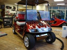 an electric golf cart with flames painted on the front and sides, parked in a garage