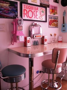 two stools sit at the bar in front of a wall with pictures on it