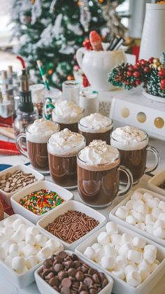 hot chocolates and marshmallows are on display at the holiday party table