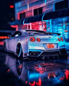 a white sports car parked in front of a building on a wet street at night