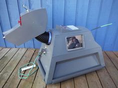 an old tv projector sitting on top of a wooden floor next to a blue wall