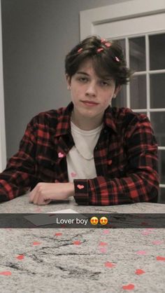 a young man sitting at a table with an emotication message written on it