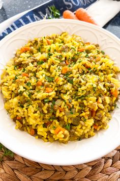 a white plate topped with rice covered in veggies and seasoning next to carrots