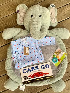 an elephant stuffed animal sitting on top of a wooden floor next to toys and books