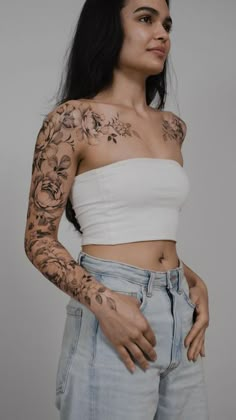 a woman with tattoos on her arms and chest is posing for the camera while wearing jeans