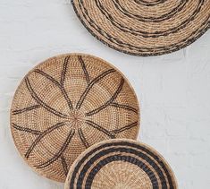 three woven baskets sitting next to each other on top of a white tablecloth covered floor