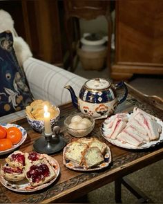 an assortment of pastries and oranges on a table with a teapot in the background