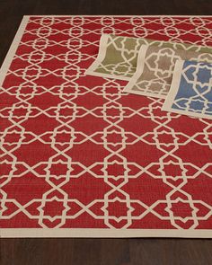 a red rug with white and blue designs on it, sitting on a wooden floor