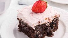 a piece of chocolate cake on a white plate with a strawberry sitting on top of it