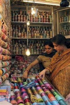 two women are shopping in a store with lots of colorful items on the shelves and around them