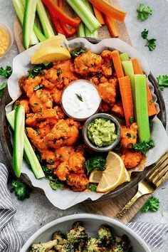 a platter filled with chicken wings, celery, carrots and cucumbers