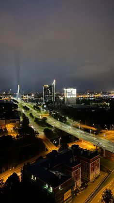 an aerial view of a city at night with the lights on and buildings lit up