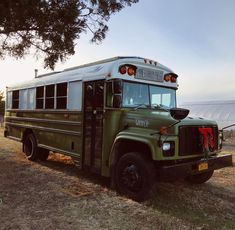 an old green school bus parked in a field