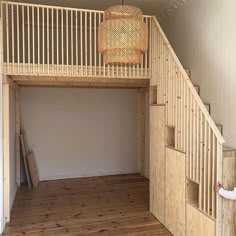 an empty room with wooden stairs and a basket hanging from the top of it's railing