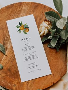 a menu card sitting on top of a wooden plate next to flowers and greenery