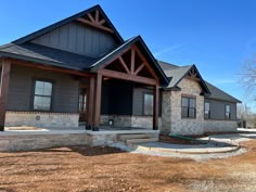 a house with stone and wood sidings on the front porch, surrounded by dry grass